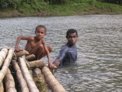 Fiji. A boy and his father pushing a bamboo raft. Shot wi... by Steven Pahel 